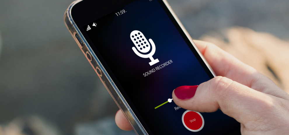 A hand holding a mobile phone with the sound recording application open on the screen