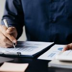 Investor sitting at a desk with documents on the table as he calculates capital gains taxes