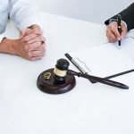 Couple sits with across a desk with a lawyer signing parentig order documents